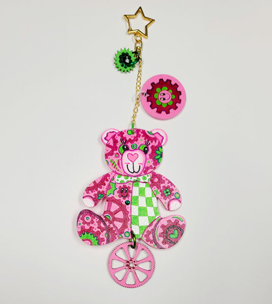 GEAR BEAR – Lovey Bag Charm

Fall in love with Lovey, the GEAR BEAR who makes the world go round with love. Hand-painted in whimsical pinks and soft greens, Lovey is covered in magical gears that symbolize the power of love in motion. The back sparkles with fine glitter, while hand-set crystals bring a luxe shimmer to her charm.